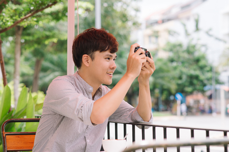 Young man photographer taking picture sitting at table in coffee shopの写真素材