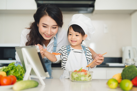 Mother with her daughter preparing lunch in the kitchen and enjoying together.の写真素材