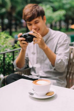 Young man photographer taking picture sitting at table in coffee shopの写真素材