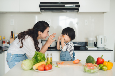Happy family in the kitchen. Mother and child daughter are preparing the vegetables and fruit.の写真素材