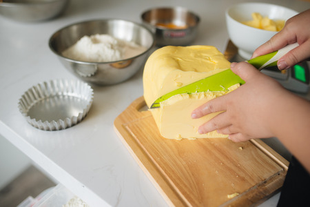 Cropped image of female chef cutting butter in kitchenの写真素材
