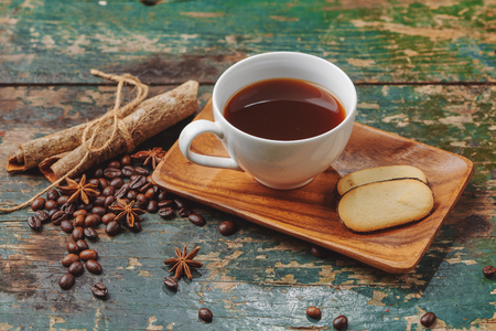 Warm coffee cup with roasted beans on rustic tableの写真素材
