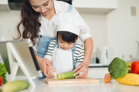 Mother with her daughter preparing lunch in the kitchen and enjoying together.の写真素材
