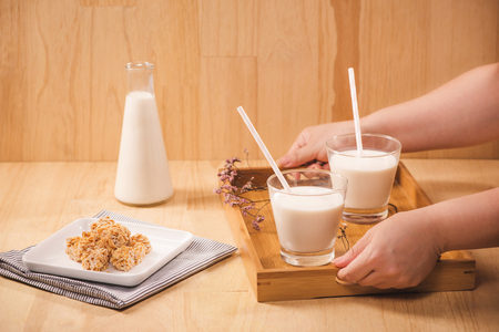 woman holding a tray with glass milkの写真素材
