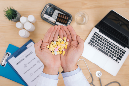 Pills in doctor hands over doctor desk tableの写真素材