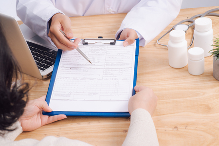 Patient and doctor taking notes on health insurance paperworkの写真素材
