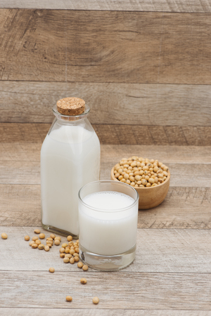 Bottle of soy milk and soybean on wooden tableの写真素材