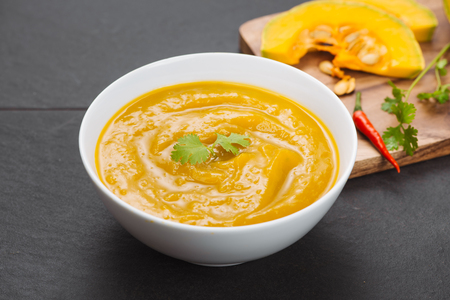 Bowl of pumpkin soup on black stone background.の写真素材