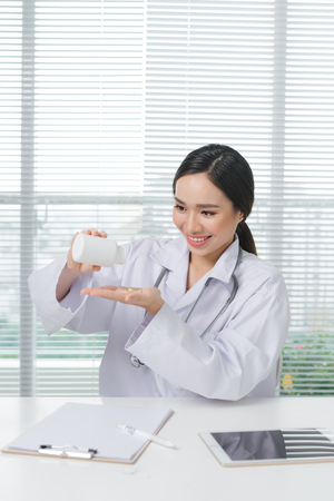 Female doctor smiling looking and holding box of medicine in her hand.の写真素材