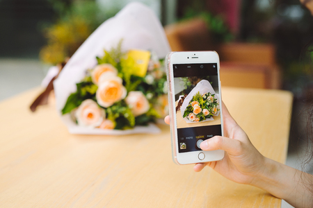 female hands taking a picture of beautiful fresh tulips with smartphone.の写真素材