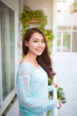 Young asian woman relaxing on a balcony  enjoying fresh air.の写真素材