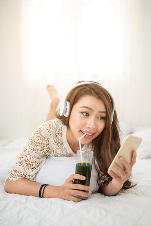 Woman Relaxing in bed and listening to music, relaxing in her living roomの写真素材