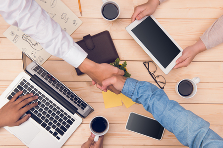 Confident business handshake. Top view of two business people shaking hands at office deskの写真素材