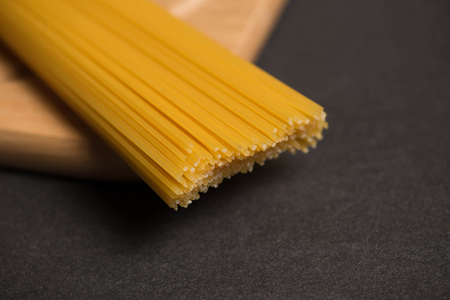 Dry spaghetti pasta tied up with rope on dark stone tableの写真素材