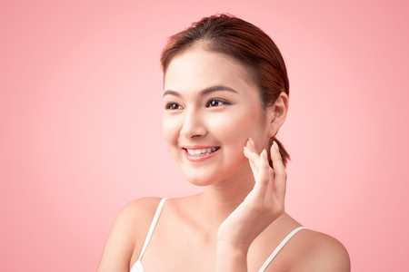 Portrait of Beautiful Skin care woman enjoy and relax touching her face on pink backgroundの写真素材