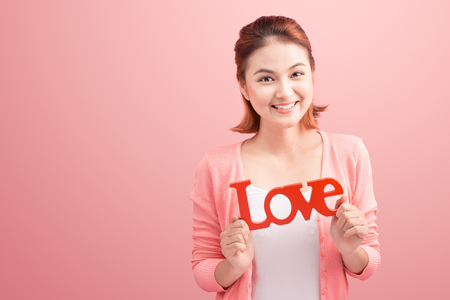Pretty asian young woman holding wooden letters LOVE on link background.の写真素材