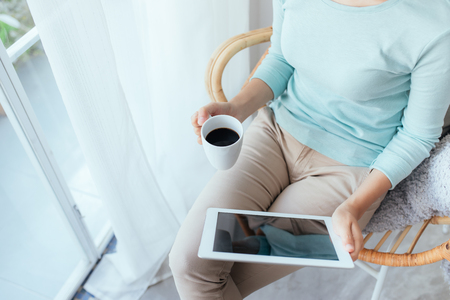 Asian young woman relaxing and using digital tablet at homeの写真素材