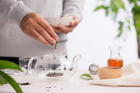 Pouring healthy tea. Hot tea on a glass teapot on a wooden table.の写真素材
