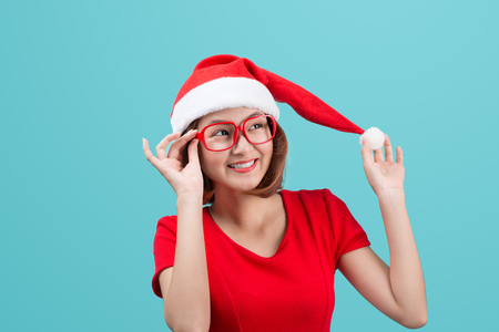 Smiling asian woman portrait with christmas santa hat isolated on blue background.の写真素材