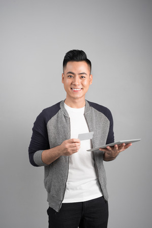 Confident young asian businessman holding digital tablet looking upの写真素材