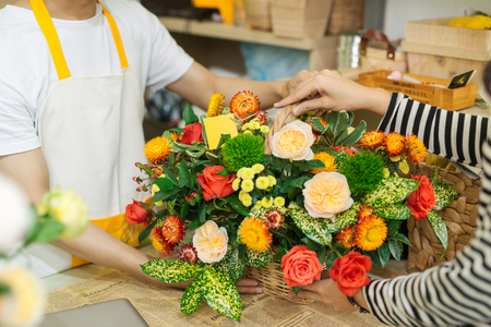 Florist giving bouquet of flower to woman in flower shopの写真素材