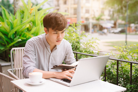 Young male freelancer working with laptop computer in comfortable coffee shopの写真素材
