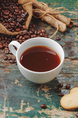 Warm coffee cup with roasted beans on rustic tableの写真素材