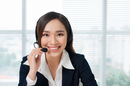Call center operators. Young beautiful asian business woman in headset.の写真素材