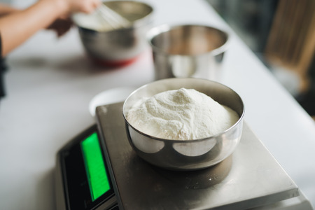 Bakery chef weighing flour on the digital scaleの写真素材