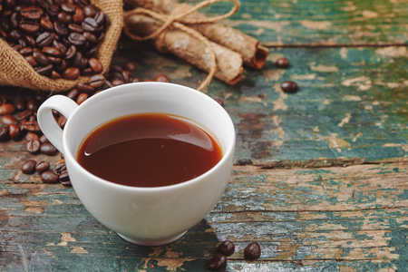 Warm coffee cup with roasted beans on rustic tableの写真素材