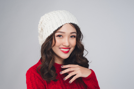 Asian woman wearing knitted warm scarf looking at camera, over gray backgroundの写真素材