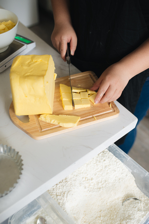 Cropped image of female chef cutting butter in kitchenの写真素材