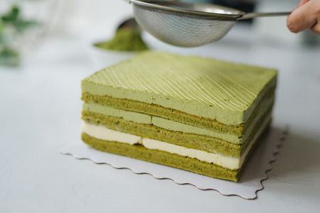 Pour green tea powder over delicious cheesecakeの写真素材