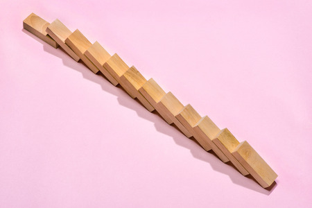 Domino block. Dominoes continuous toppled on pink background.の写真素材