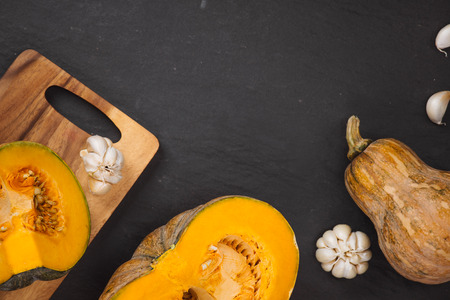 Cut Pieces of Pumpkin with seeds in Wooden Plate on the Wooden Board.Harvest,Fresh Vegetable, Ingredient.White Food Background.Top Viewの写真素材