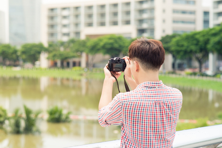 Half length of young asian man outdoor in the city taking pictureの写真素材