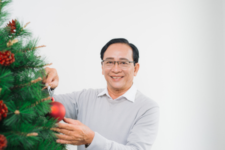 Happy senior asian man decorating christmas tree.の写真素材