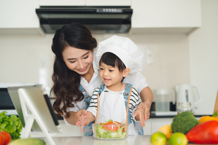 Mother with her daughter preparing lunch in the kitchen and enjoying together.の写真素材