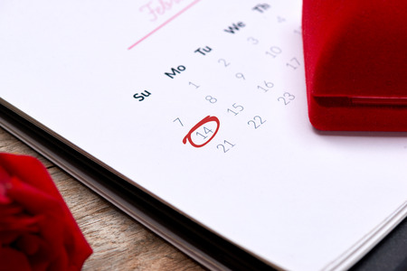 14th of February on calendar date . Red rose, hearts and gift box on wooden table. Valentine.の写真素材