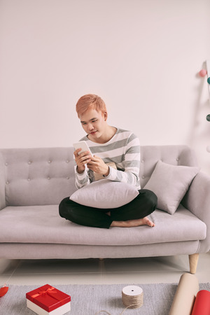 Happy man holding gift box and using smartphone on the table. Asian man preparing presentsの写真素材