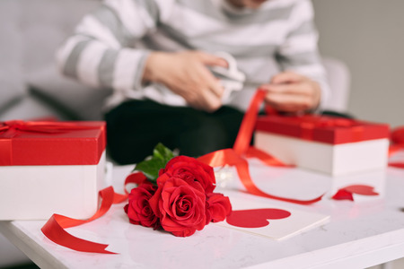 Male hands wrapping Valentine handmade present in paper with red ribbonの写真素材