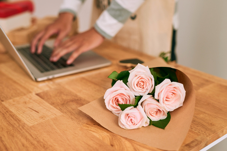 Male florist working with laprop at workplace in flower shopの写真素材