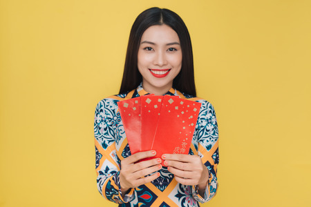 Attractive Vietnamese woman wearing traditional costume, isolated on yellow backgroundの写真素材