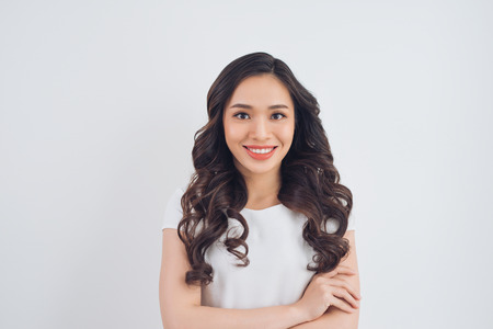 Portrait of Vietnamese young woman smiling with arms crossed by wallの写真素材