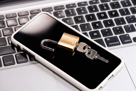 Smartphone and padlock is lying on a laptop keyboardの写真素材