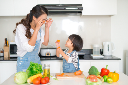 Mother with her daughter in the kitchen cooking togetherの写真素材