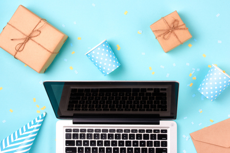 Gift box, birthday party things and laptop on a blue backgroundの写真素材
