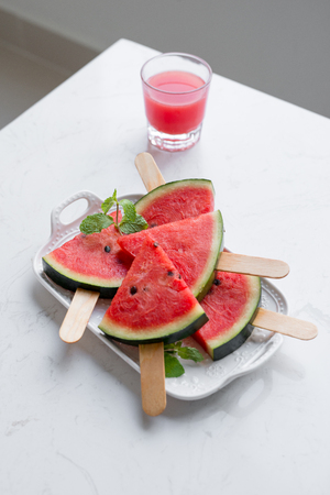 Fresh red smoothie in a glass with sliced pieces of watermelon on table.の写真素材
