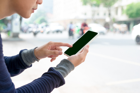 Businessman using his smartphone, showing blank screen outdoors.の写真素材