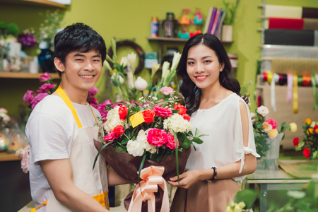 Male florist offering flowers at the counter in the florist shopの写真素材